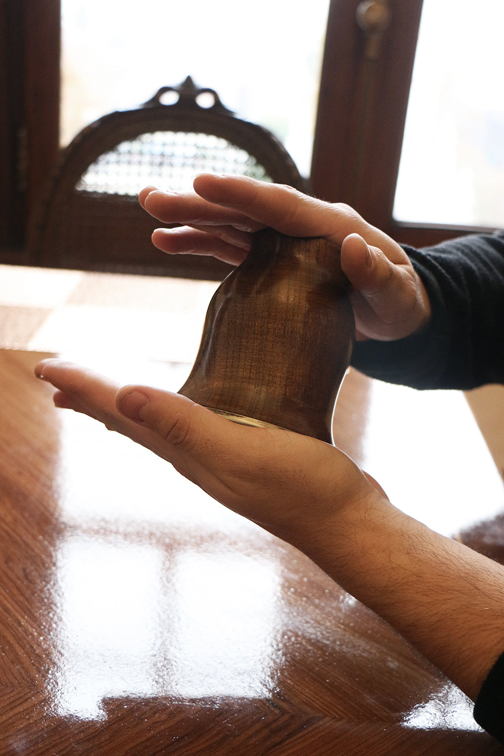 Person's hands gently holding and showcasing a crafted wooden mate cup