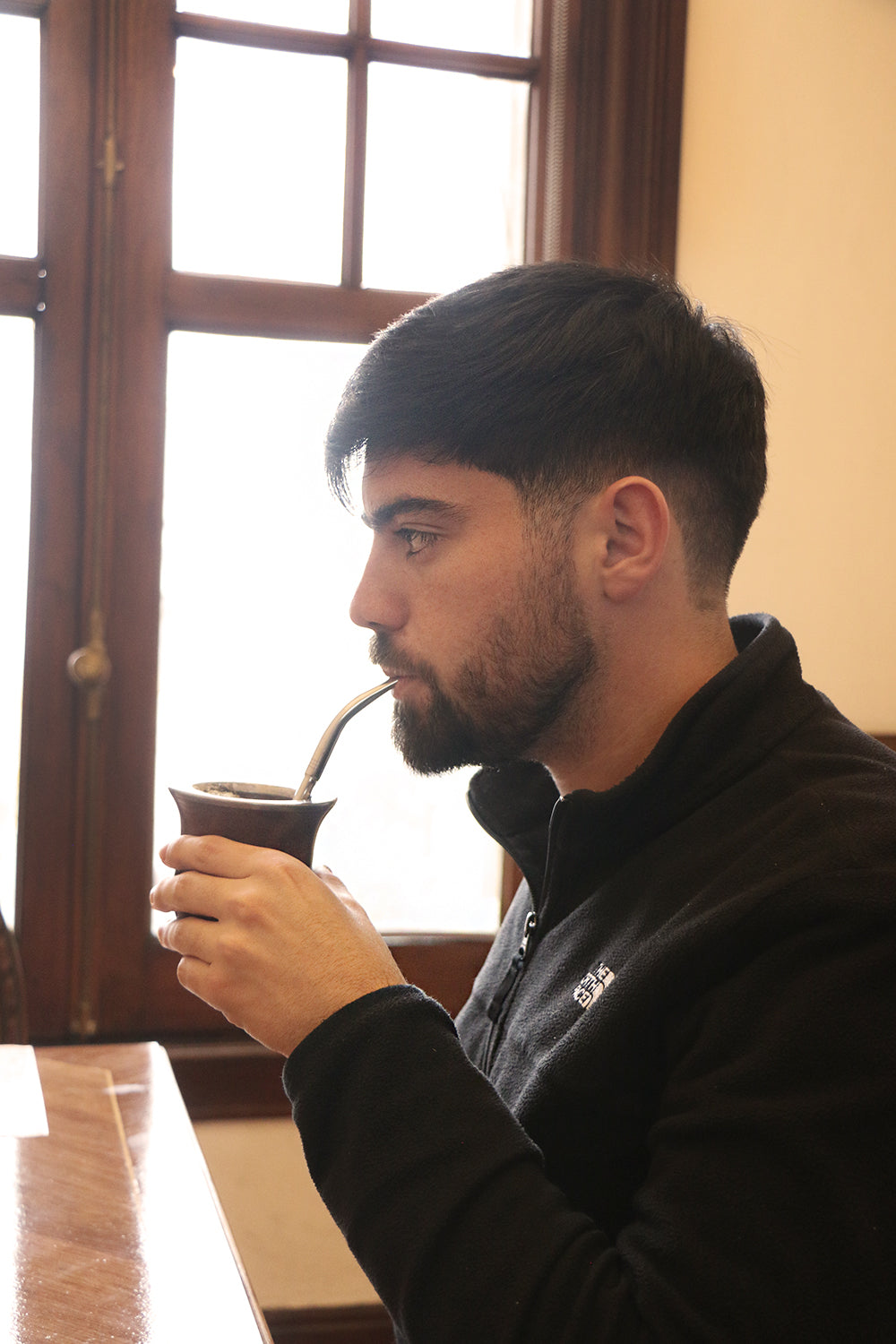 Young man drinking traditional yerba mate from a wooden cup with a metal straw